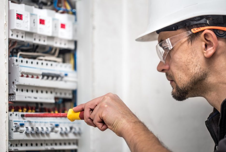 man electrical technician working switchboard with fuses installation connection electrical equipment close up